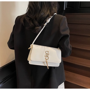 Close-up of white leather crossbody bag with gold SSS metal logo and fringe detail