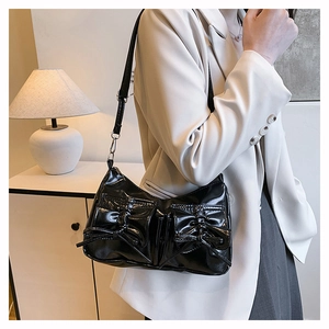 Gros plan sur le sac à bandoulière en cuir verni noir avec deux nœuds décoratifs élégants