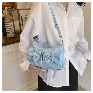 Détail du sac porté épaule bleu clair brillant avec poches à nœuds dans un café