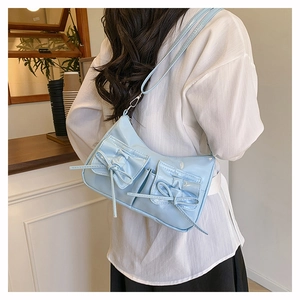 Close-up of a light blue bow-accented crossbody bag worn over a shoulder in a cafe