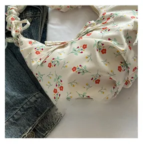 Detail showing the floral fabric texture and ruffled handle of the cream tote bag