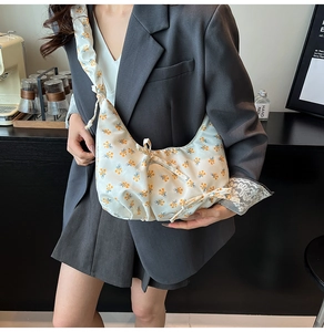 Detail of floral dumpling bag featuring bow tie closure and ruched shoulder strap