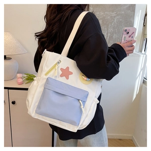 Detail der weiß-blauen Tragetasche mit mehreren Taschen und süßen Sternen-Patches