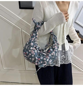 Dettaglio di borsa tote blu scuro a fiori con spallina regolabile con fiocco