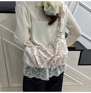 Dettaglio della borsa in tela floreale con bordo in pizzo bianco e motivi rossi