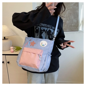 Detail of blue and pink nylon crossbody tutor bag with star patch and smiley charm