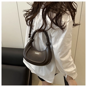 Detail view of the brown crescent bag with white Fashion print and smooth leather texture