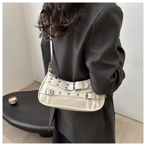 Detail of cream shoulder bag with twin buckles and metal eyelets on gray blazer