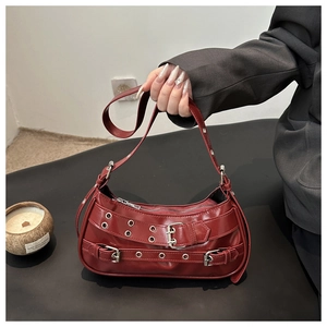 Detail of dark red punk style bag showing metal buckles and eyelets on leather texture