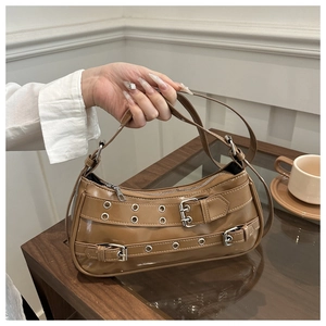 Close-up of brown vintage crescent bag with silver rivet belts and white stitching