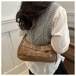 Detailed view of brown retro shoulder bag with silver buckles and metal eyelets decoration