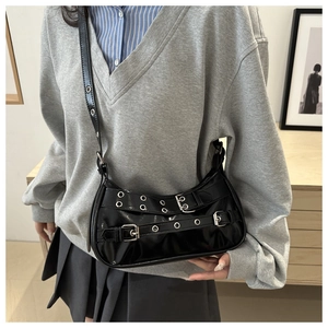 Detail of black patent leather hobo bag with punk metal eyelets and decorative buckles