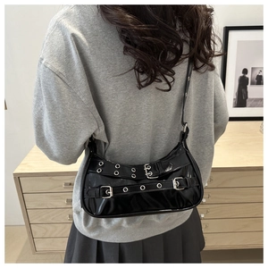 Detail of black glossy patent leather shoulder bag with punk rivets and metal buckles