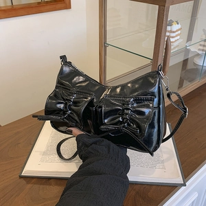 Sac à main chic en cuir verni noir avec nœuds et fermeture éclair argentée sur bois