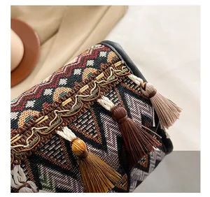 Détail macro d'un sac tissé ethnique avec ruban brodé et pompons multicolores