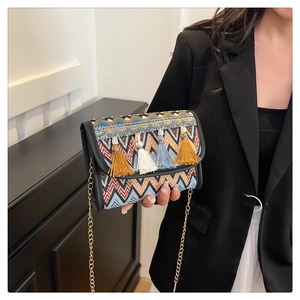 Gros plan du sac bandoulière tissé ethnique avec motifs géométriques et pompons