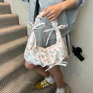 Borsa tote floreale bianca con volant e fiocchi scattata in una scena interna