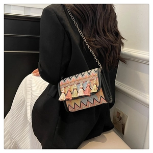 Détail d'un sac à bandoulière tissé coloré avec glands boho et chaîne dorée sur mannequin