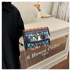 Détail d'un sac bandoulière tissé ethnique avec glands et chaîne dorée élégante