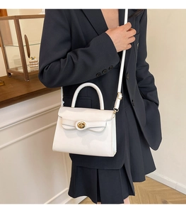 Detail of the elegant white leather handbag showing gold twist lock and shoulder strap
