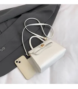 Detailed top view of a cream-white mini crossbody bag showing size comparison with a phone
