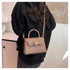 Detail of a brown leather trapezoid handbag with gold twist-lock and shoulder strap