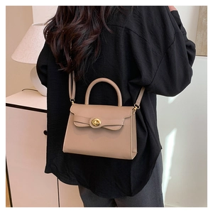 Detail of elegant khaki leather handbag with gold circular twist lock and adjustable strap