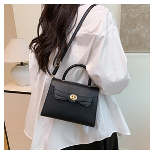 Chic black leather crossbody bag with vintage gold clasp worn by model in home setting