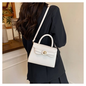 Close-up of a white leather Kelly bag with golden turn-lock on a black blazer outfit