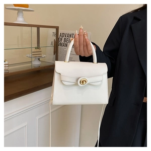 Detail of a white crossbody handbag featuring a golden clasp and elegant top handle