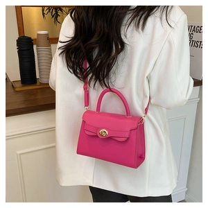 Close-up of rose pink kelly style bag with gold twist lock and top handle detail