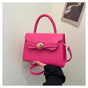 Close-up of hot pink matte leather handbag featuring a golden circular twist lock buckle