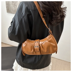 Detail of a brown patent leather pleated bag with a large metallic belt buckle
