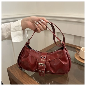 Close-up of deep red pleated leather baguette bag with silver metal buckle and eyelets