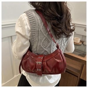 Macro view of dark red leather pleated bag featuring vintage metal buckle and texture
