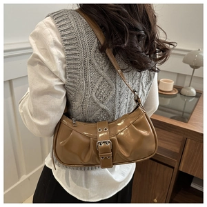 Detailed view of brown glossy crescent bag with vintage buckle and pleated leather texture