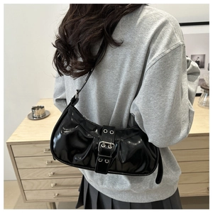 Detailed view of black pleated underarm bag with silver buckle worn by a model