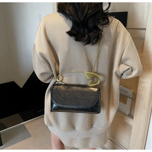Vue détaillée du sac bandoulière en cuir verni noir avec poignée trombone dorée et chaîne
