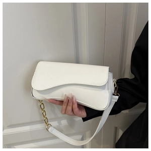 Detail of white PU leather crossbody bag featuring a wavy flap and gold metal chain strap