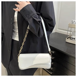 Macro detail of a white shoulder bag with a wave-shaped flap and gold chain strap