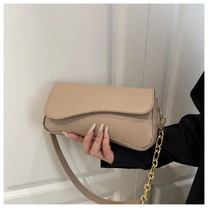 Detail of beige underarm bag with unique wavy flap, leather strap and gold chain link