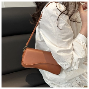 Brown baguette shoulder bag featuring a unique wavy bottom design on a white lace top