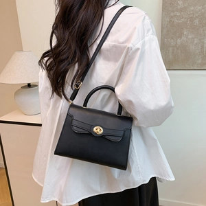 Classic black leather handbag with gold twist lock shown as crossbody on a model