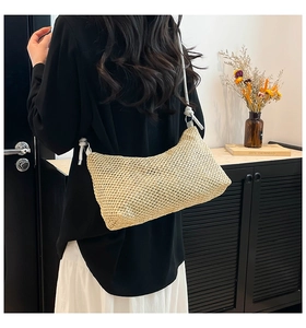 Detail of hand-woven straw crossbody bag with knot shoulder strap and natural fiber texture