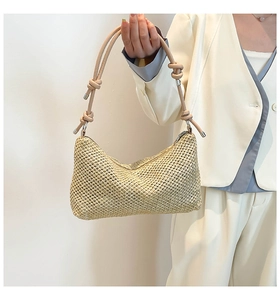 Detail of woven straw tote bag with decorative knot strap and secure metal zipper