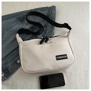 White nylon crossbody bag shown with denim jacket and phone for size scale