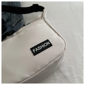 Close-up of durable white nylon fabric with a black Fashion label on crossbody bag