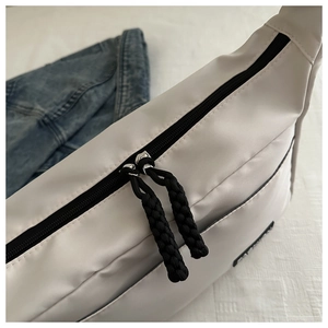 Detail of white nylon crossbody bag featuring black zipper and woven rope puller