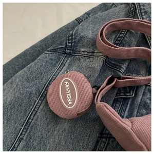 Close-up of pink corduroy dumplings bag detail with brand label on denim background