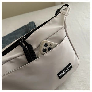 Detail showing white nylon crossbody bag front zipper pocket with phone inside for capacity